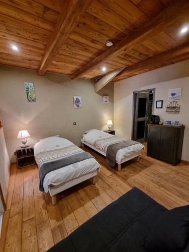 deux lits dans une chambre avec un plafond en bois dans l'établissement Chambres d'hôtes Le St Maurice, à Truinas