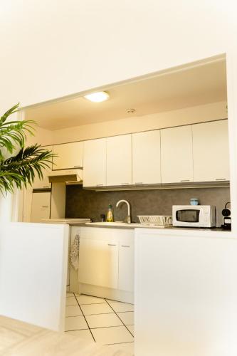 une cuisine avec des armoires blanches et un micro-ondes dans l'établissement Charmant appartement Chalonnais- Proche de la gare, à Chalon-sur-Saône