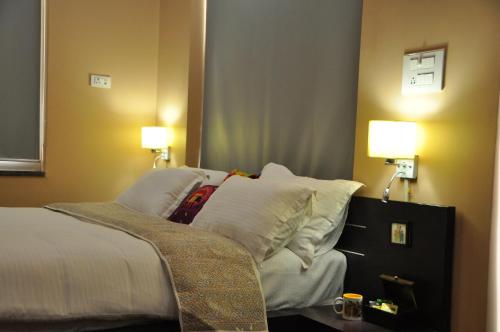 a bedroom with a bed with white pillows and two lamps at Shardas Homestay in Ajmer