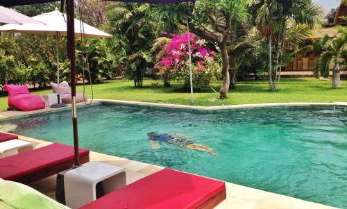 a person is swimming in a swimming pool at Rhipidura Bungalows by Phocéa in Pemuteran