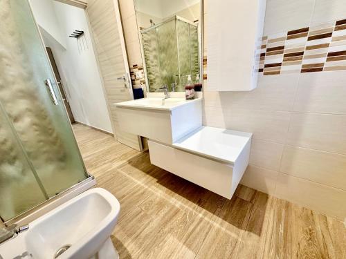 a white bathroom with a sink and a shower at Queen E in Follonica