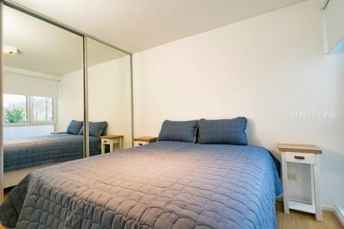 1 dormitorio con 1 cama grande y espejo en Del Bosque en Ushuaia