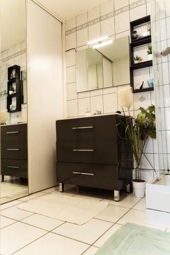 La salle de bains est pourvue d'une coiffeuse noire et d'un miroir. dans l'établissement Charmant appartement Chalonnais- Proche de la gare, à Chalon-sur-Saône