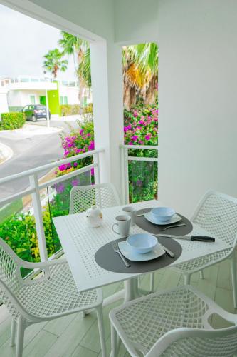 a white table and chairs on a balcony with flowers at Piscadera Harbour Village in Willemstad