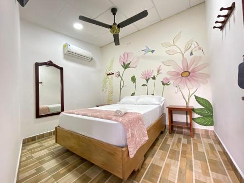 a bedroom with a bed with flowers on the wall at Hotel BJ Curumani in Curumaní