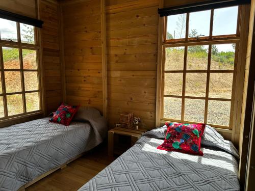 two beds in a log cabin with windows at KUYAY in Ráquira