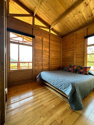 a bedroom with a bed in a wooden cabin at KUYAY in Ráquira