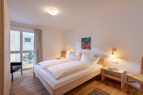 a white bedroom with a bed and a window at Appartement Naturbunt in Söll