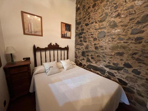 Ce lit se trouve dans un dortoir doté d'un mur en pierre. dans l'établissement Casal de Agra, à Bergondo