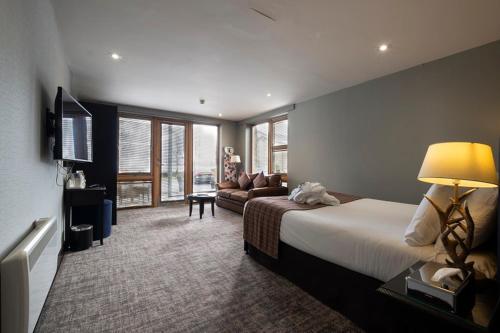 Habitación de hotel con cama y sofá en The Lodge On Loch Lomond Hotel en Luss