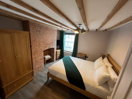 a bedroom with a bed and a brick wall at Beaumond Cross Inn in Newark upon Trent