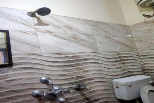 bagno con servizi igienici e parete in pietra di Hotel New Ashiyana Palace Varanasi Near Railway Station 400m a Varanasi