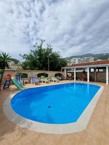 a large blue swimming pool with chairs and a slide at Mila & Aleksandr Apartments in Budva