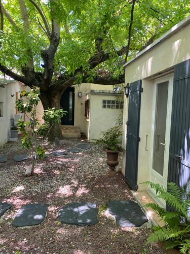 une cour avec des rochers devant une maison avec un arbre dans l'établissement Maison Sainte Geneviève, à Pernes-les-Fontaines