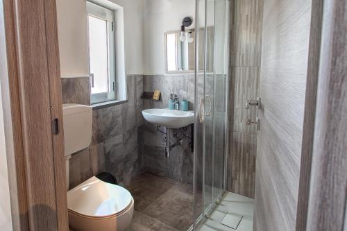 a bathroom with a toilet and a sink and a shower at Tredici Guest House in Favara