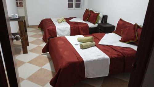 a room with three beds with red and white sheets at Hotel Colonial El Bosque in Tunja