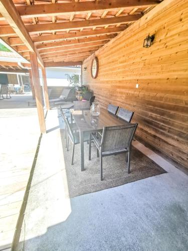 d'une terrasse avec une table, des chaises et un mur en bois. dans l'établissement La Fourmi - Maison avec piscine à Lacanau Lac, à Lacanau
