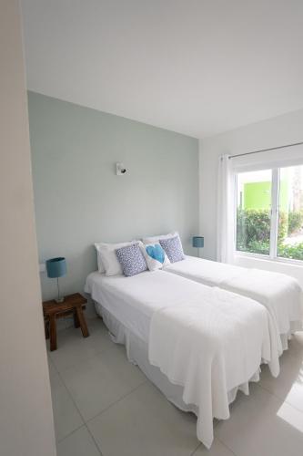 two beds in a white room with a window at Piscadera Harbour Village in Willemstad