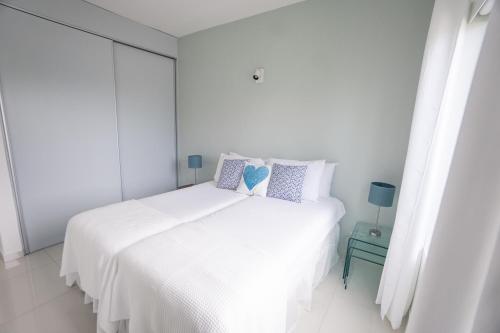 a white bedroom with a large white bed with pillows at Piscadera Harbour Village in Willemstad
