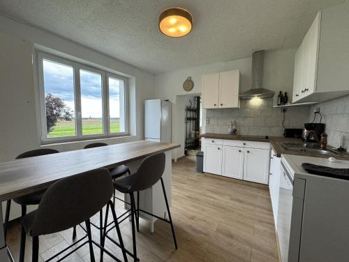 une cuisine avec des placards blancs et un comptoir avec des tabourets de bar dans l'établissement La Pâquerie - Gite - Campagne - 12 pers - Rêve au Mans, à Saint-Vincent-du-Lorouër