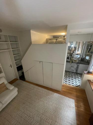 Cette chambre blanche dispose d'un lit et d'un canapé. dans l'établissement Élégant studio avec mezzanine porte des Ternes, à Paris