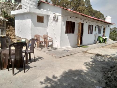 a small white house with chairs and a table at Peacock Homestay in Srīnagar