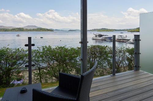 a porch with two chairs and a view of the water at The Lodge On Loch Lomond Hotel in Luss