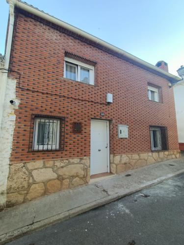 a brick building with a white door on a street at Alojamiento Rural El Cerro in Fresneda de la Sierra