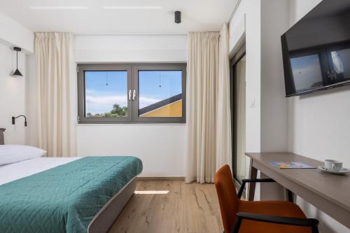 a hotel room with a bed and a desk and a window at Apartmani Vila Mara M 4 heated pool and whirpool in Omišalj