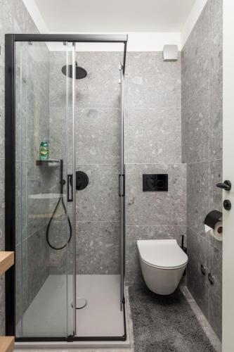 a bathroom with a glass shower with a toilet at Apartmani Vila Mara M 4 heated pool and whirpool in Omišalj