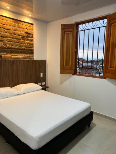 a bedroom with a large bed and a window at Hotel Fenix in Ocaña