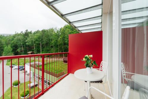a balcony with a white table and a red railing at Familienhotel Trebesingerhof in Trebesing