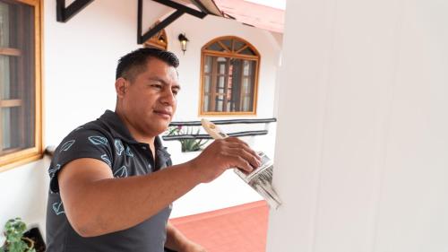 a man standing in front of a house holding a brush at Hotel Galapagos Suites B&B in Puerto Ayora