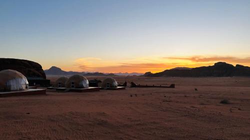 a group of tents in the desert at sunset at wadi rum fox road camp & jeep tour in Wadi Rum