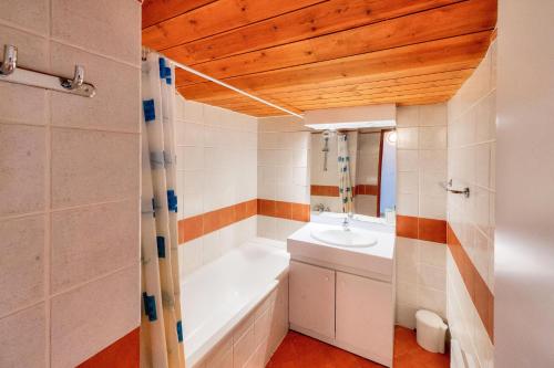 une salle de bain avec une baignoire et un lavabo dans l'établissement Résidence Les Chalets de Puy Saint Vincent - maeva Home - Appartement 3 Pièces 6 Personnes - Confort MAE-6380, à Narreyroux