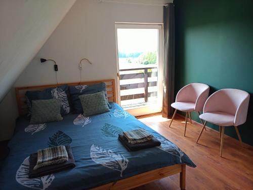 um quarto com uma cama com 2 cadeiras e uma janela em Chalet avec vue unique em Kętrzyn