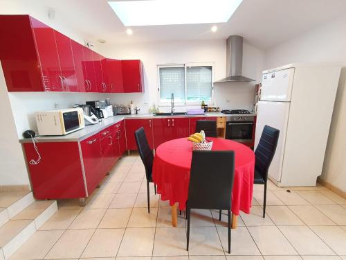 een keuken met rode kasten en een rode tafel met stoelen bij le calme de la campagne bretonne, wifi, netflix, 4 lits, freebox revolution, draps, café, thé in Guer