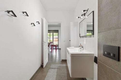 ein weißes Badezimmer mit einem Waschbecken und einem Spiegel in der Unterkunft Magie de Moorea Serenite in Temae