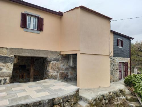 a house with a stone wall and a patio at Casa do Moinho in Resende