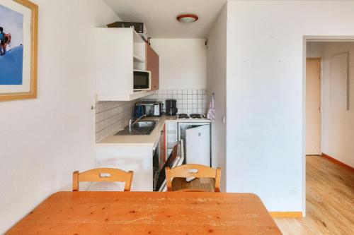 une cuisine avec une table en bois et deux chaises dans l'établissement Résidence Le Hameau des Ecrins - maeva Home - Appartement 2 Pièces 6 Personnes - Confort MAE-6159, à Puy-Saint-Vincent