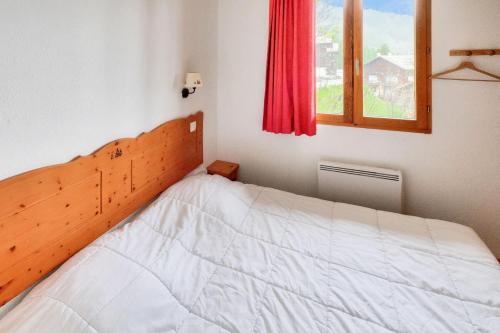 une chambre avec un lit avec une tête de lit en bois et une fenêtre dans l'établissement Résidence Le Hameau des Ecrins - maeva Home - Appartement 2 Pièces 6 Personnes - Confort MAE-6159, à Puy-Saint-Vincent