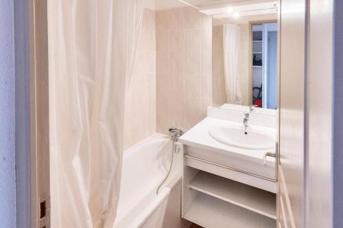 une salle de bain blanche avec un lavabo et un miroir dans l'établissement Résidence Le Hameau des Ecrins - maeva Home - Appartement 2 Pièces 6 Personnes - Confort MAE-6159, à Puy-Saint-Vincent