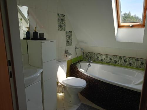 uma casa de banho com um WC, uma banheira e um lavatório. em Chalet avec vue unique em Kętrzyn