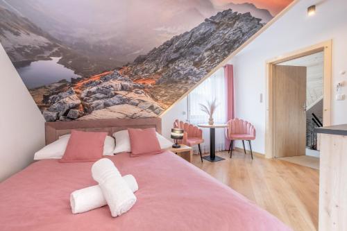 um quarto com uma cama rosa e um mural de montanha na parede em Apartamenty Górskie Widoki em Poronin