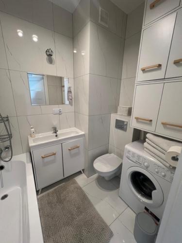 bagno con lavandino e servizi igienici e lavatrice. di Tani Nocleg Ełk - Apartament I love Ełk a Ełk