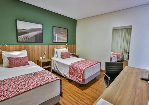 a hotel room with two beds and green walls at Comfort Mogi Guaçu in Mogi Guaçu