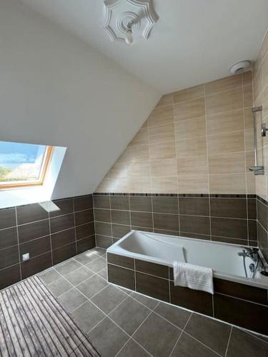 La grande salle de bains est pourvue d'une baignoire et d'une fenêtre. dans l'établissement Maison conviviale, à Mont-près-Chambord