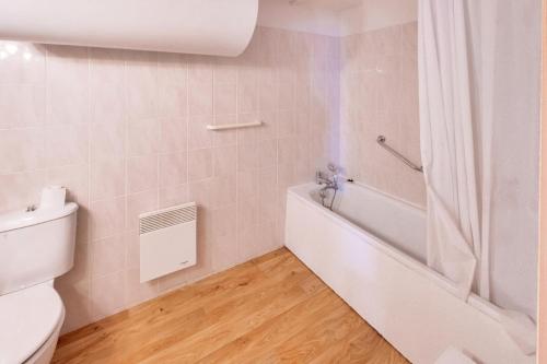 une salle de bain avec une baignoire blanche et des toilettes dans l'établissement Résidence Le Hameau des Ecrins - maeva Home - Appartement 2 Pièces 4 Personnes - Confort MAE-7064, à Puy-Saint-Vincent