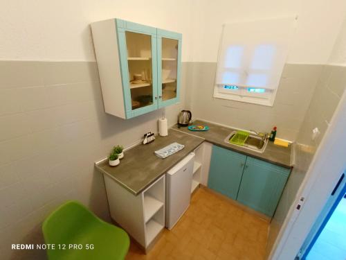 MiniaにあるSpasmata Apartments no cookingの小さなキッチン(シンク、緑の椅子付)