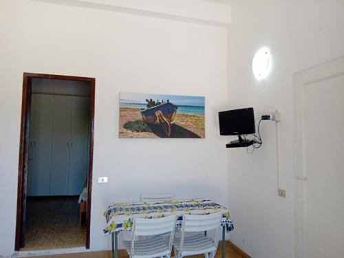 a room with a table with chairs and a television at Villa Rosa in Castellammare del Golfo